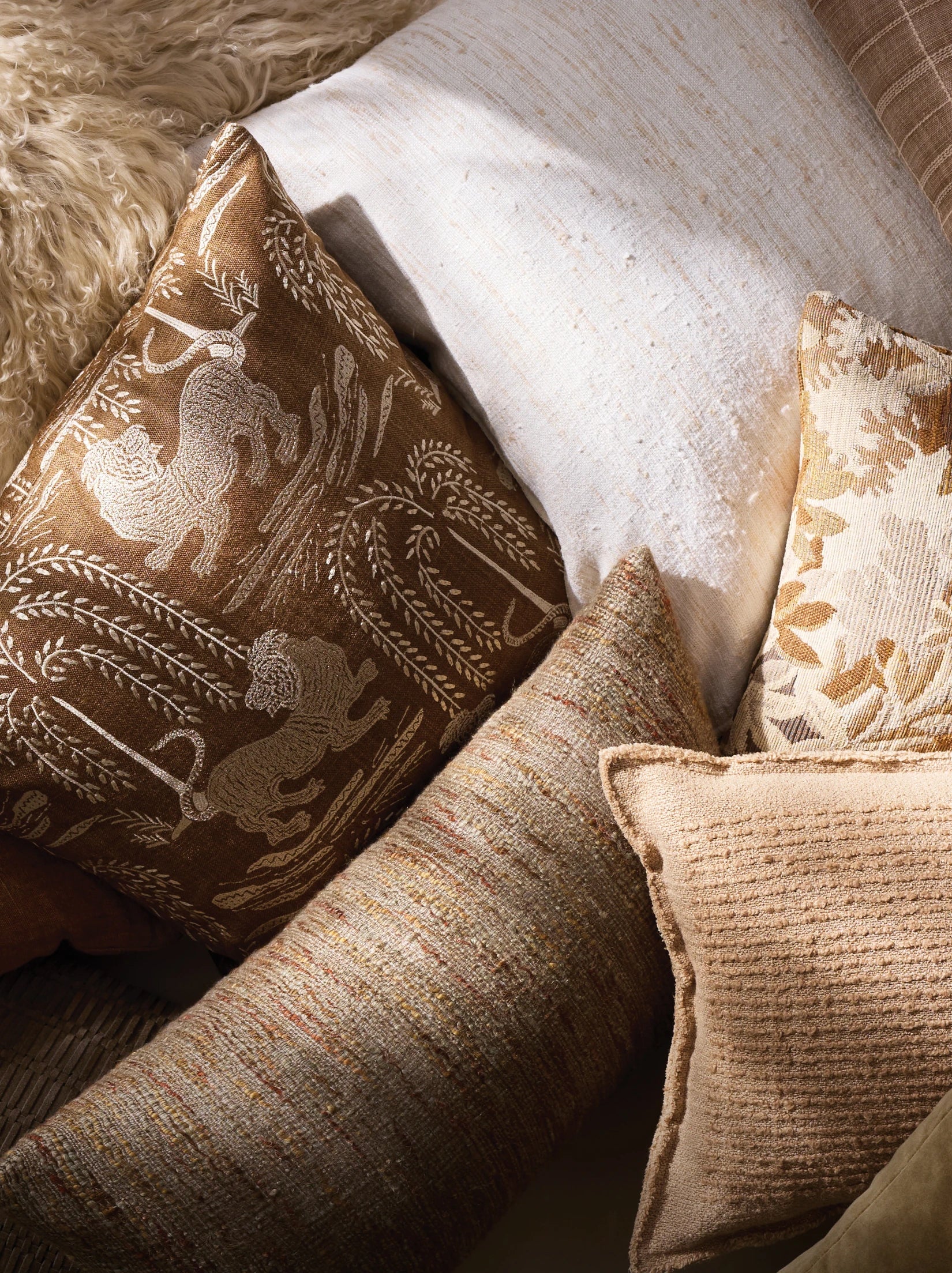Close-up of assorted decorative pillows in warm tones with textured and patterned fabrics.