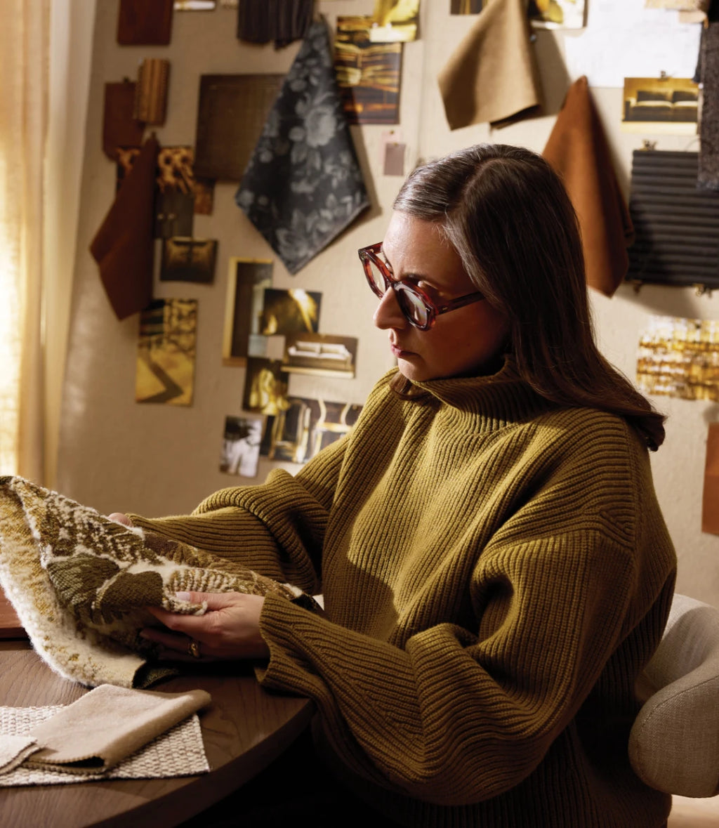 An interior designer examines fabric samples in her interior design studio, surrounded by a curated wall display of textiles, materials, and design swatches that showcase her expertise in creating custom interior spaces.RetryClaude can make mistakes. Please double-check responses.