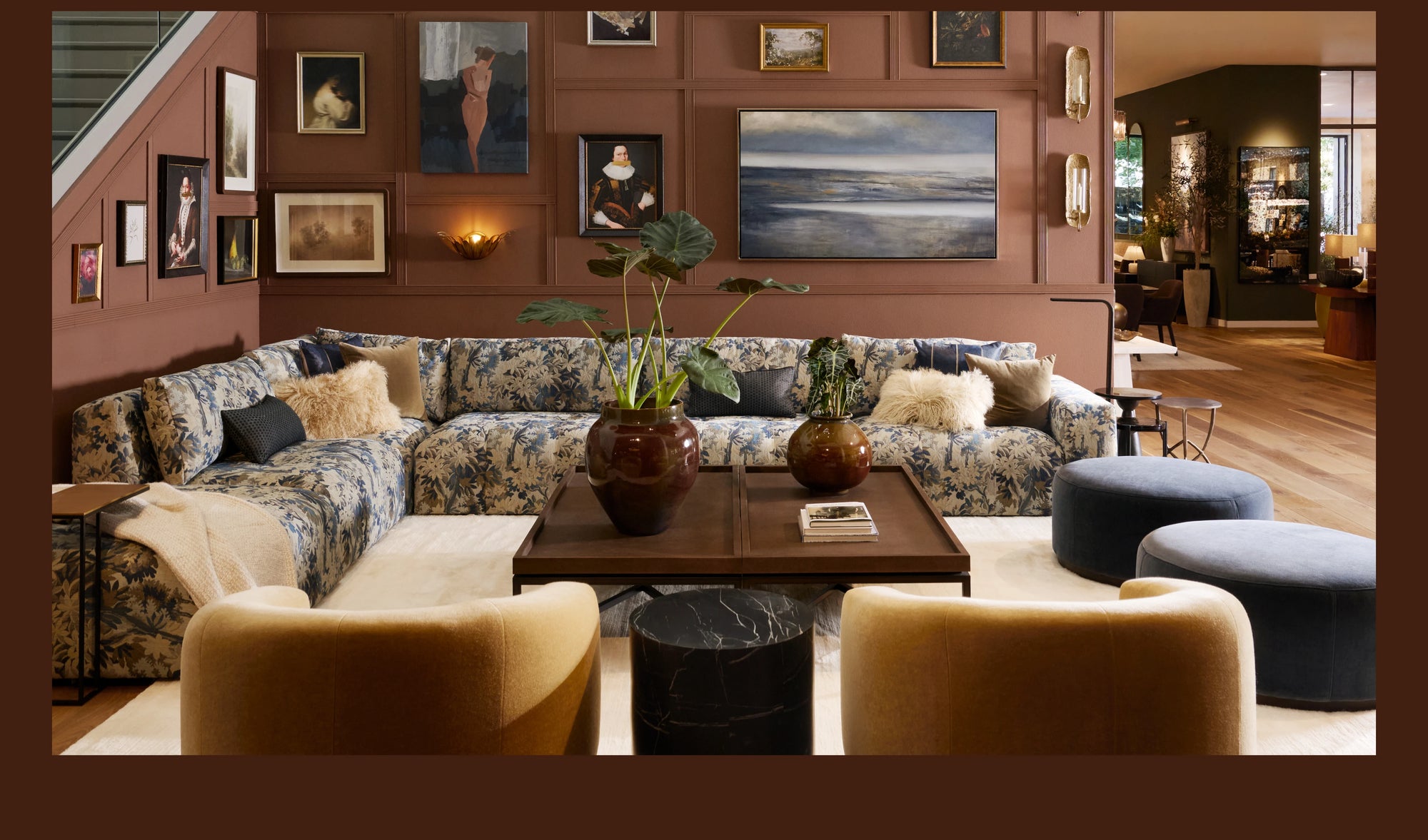 Arhaus showroom living room featuring a floral-patterned sectional, layered accent seating, sculptural coffee tables, and an art-filled wall in warm, earthy tones.
