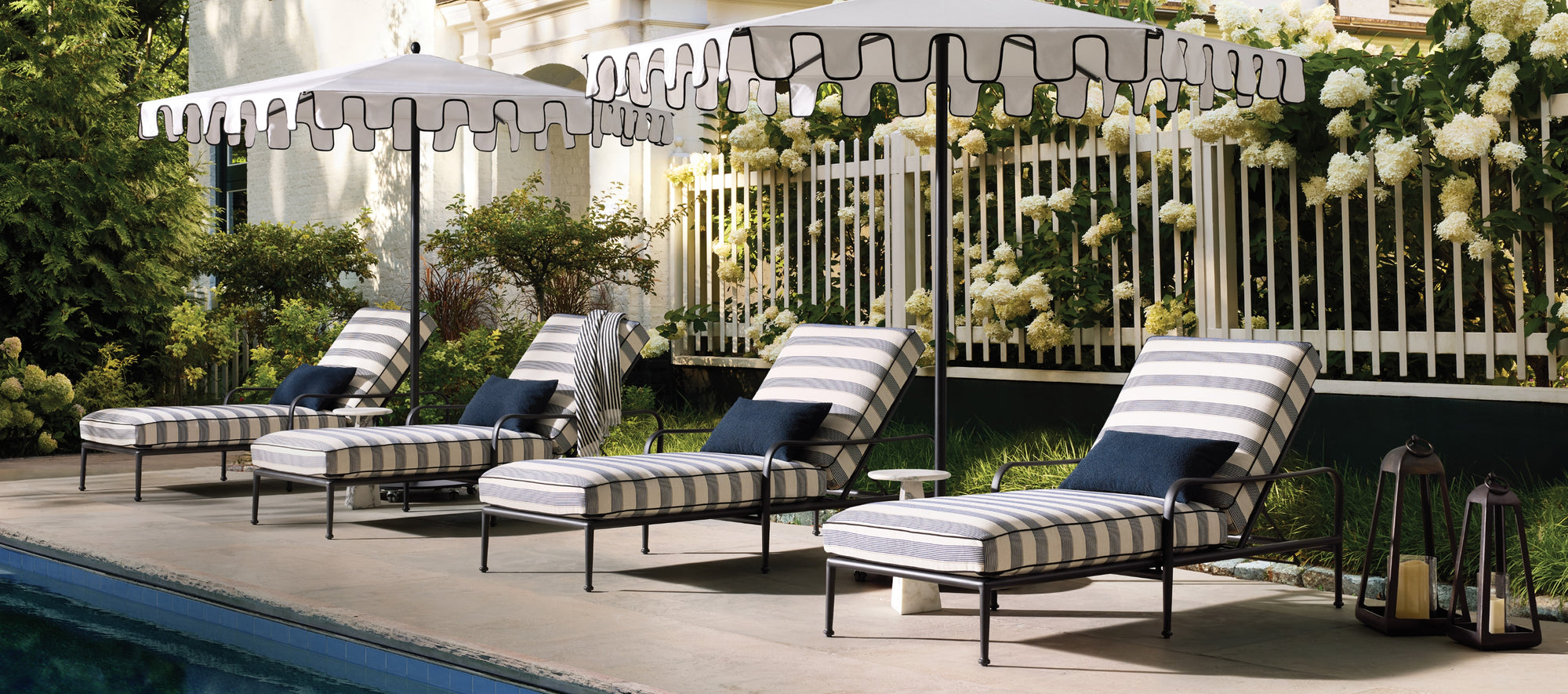 Expansive outdoor living space featuring cushioned seating, warm wood tones, and layered textiles, set in a bright, open-air environment.