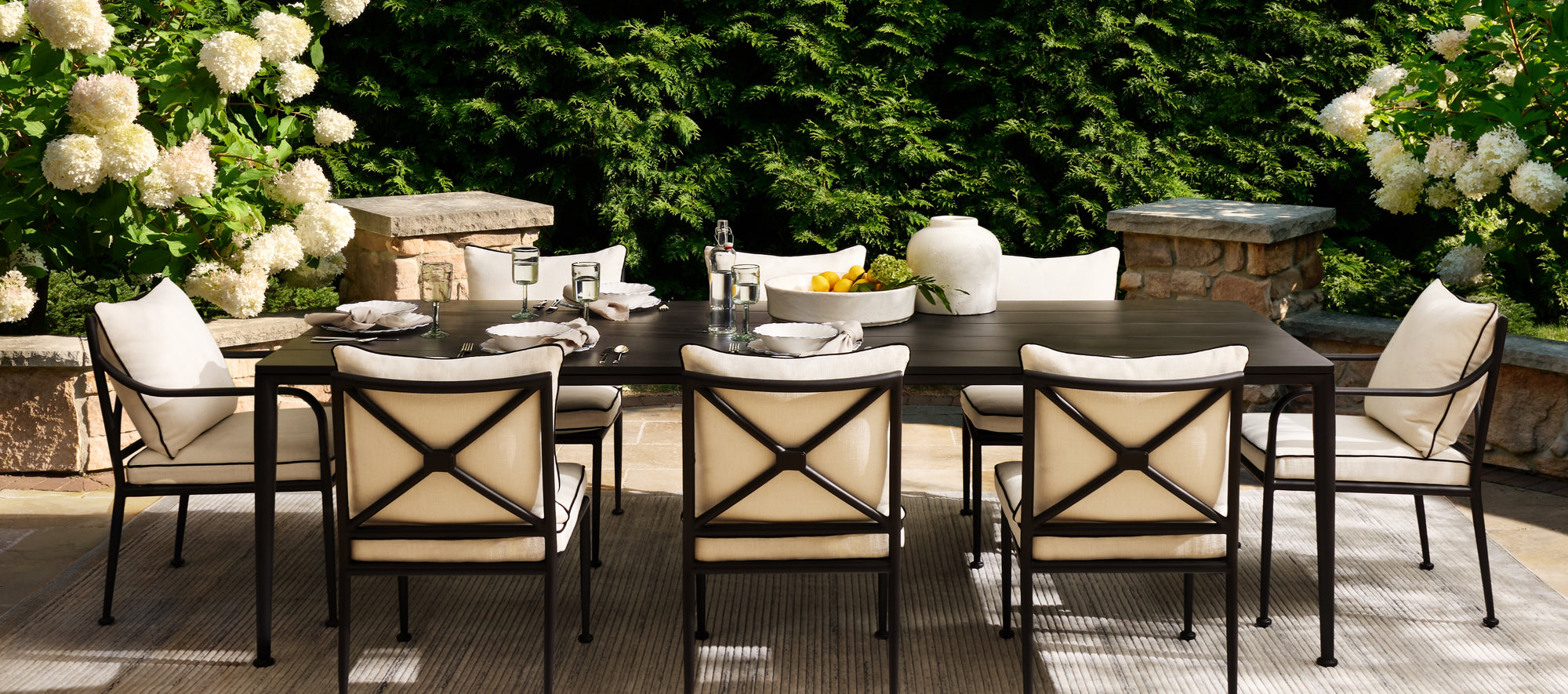 Outdoor dining space featuring cushioned seating, aluminum dining table, and natural materials, creating a relaxed and elevated open-air environment.
