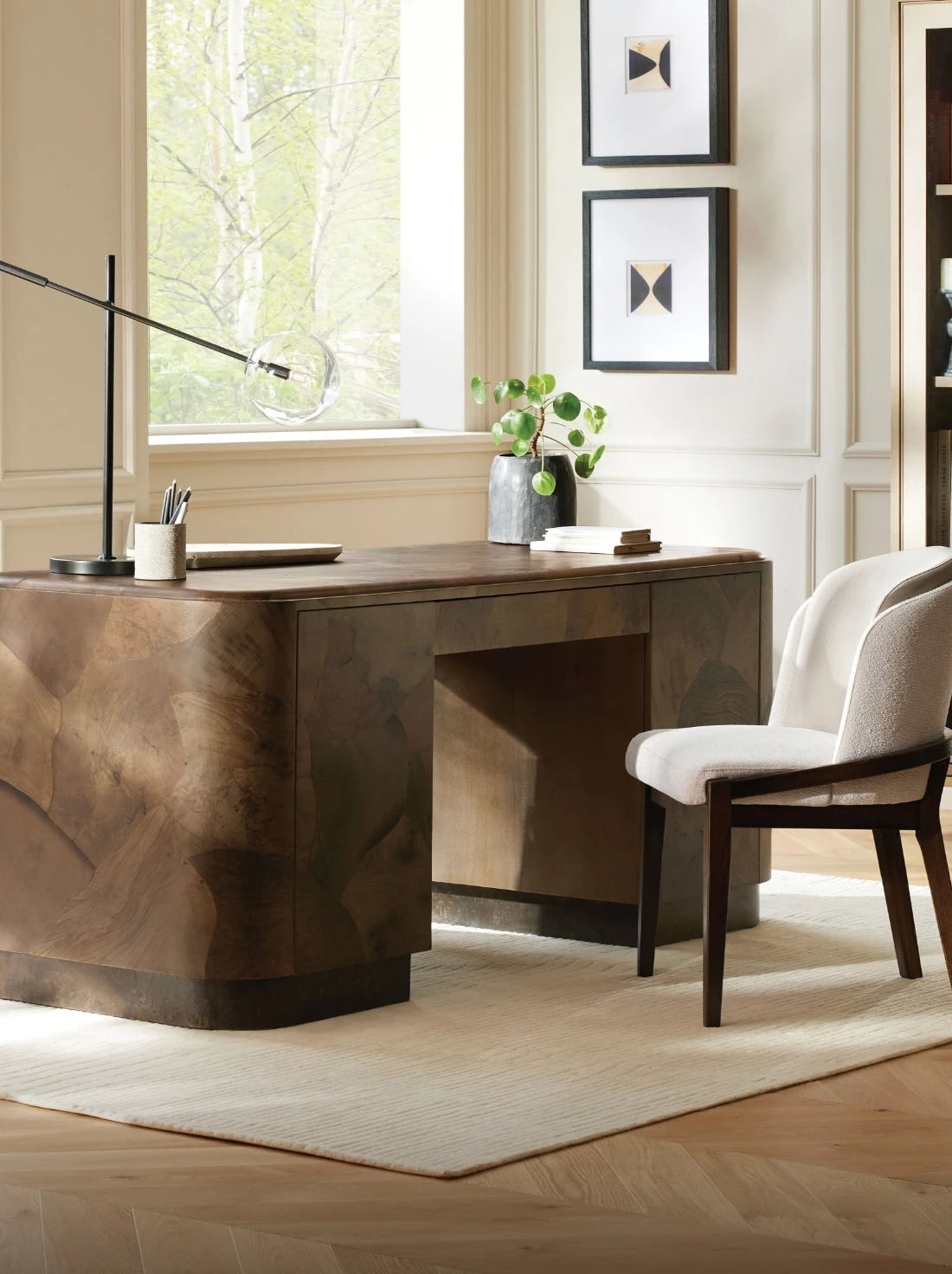 Stylish home office with a wooden desk, cushioned chair, and large window overlooking greenery.