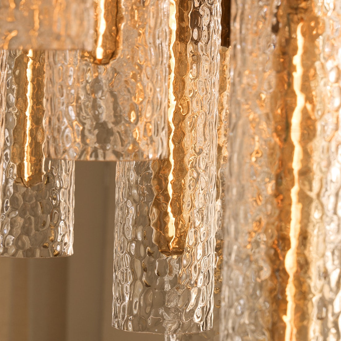 Close-up of a statement lighting fixture with textured glass and warm metallic detailing, casting a soft ambient glow. 
