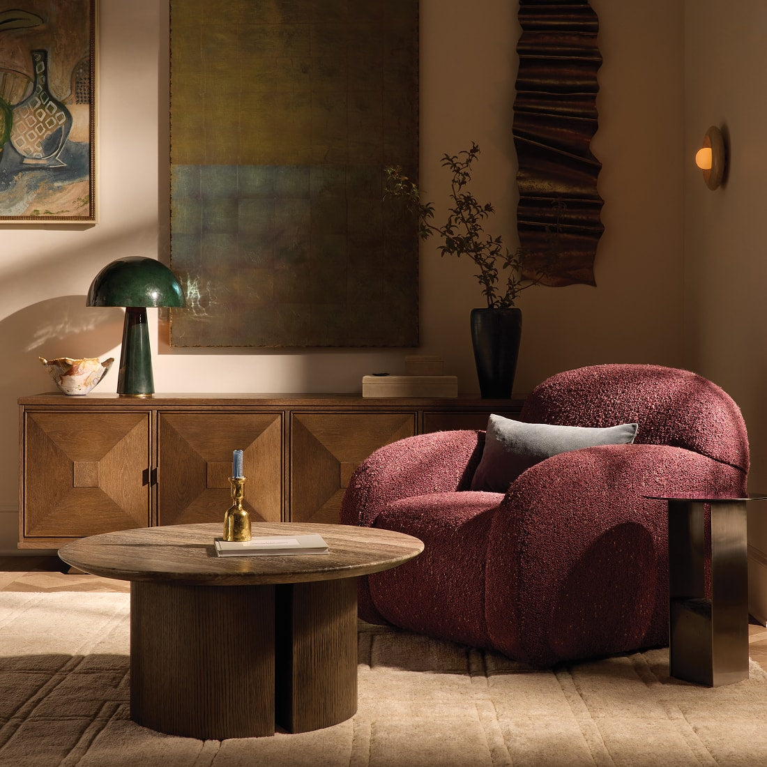 Living room featuring a sculptural upholstered lounge chair, warm wood furnishings, and layered artwork, styled with rich textures and dramatic autumn-inspired tones.