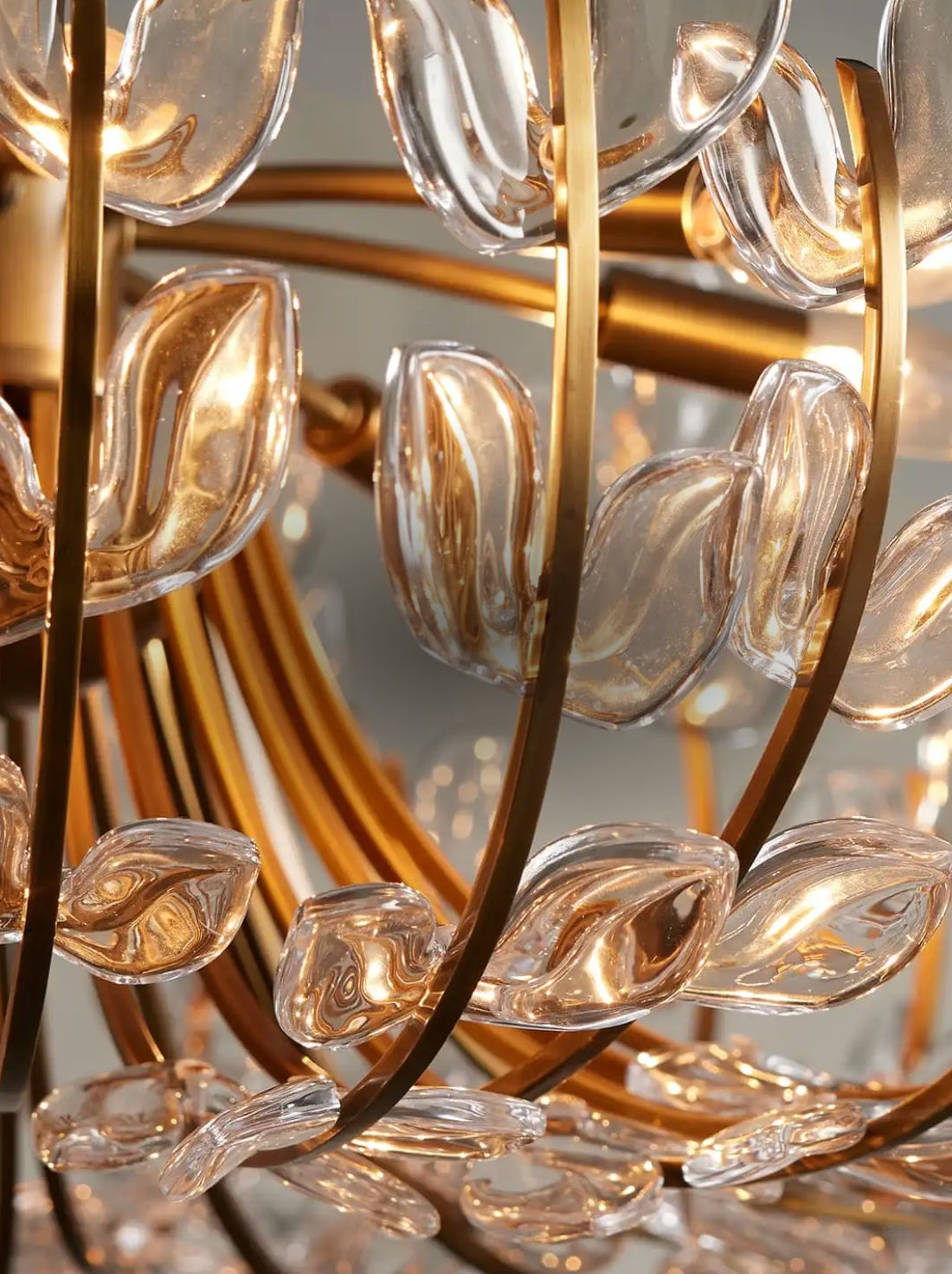Close-up of a golden chandelier with curved glass petals, reflecting warm light. The intricate design conveys elegance and sophistication.